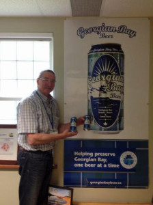 Mayor Braid standing in front of large poster for georgian bay beer